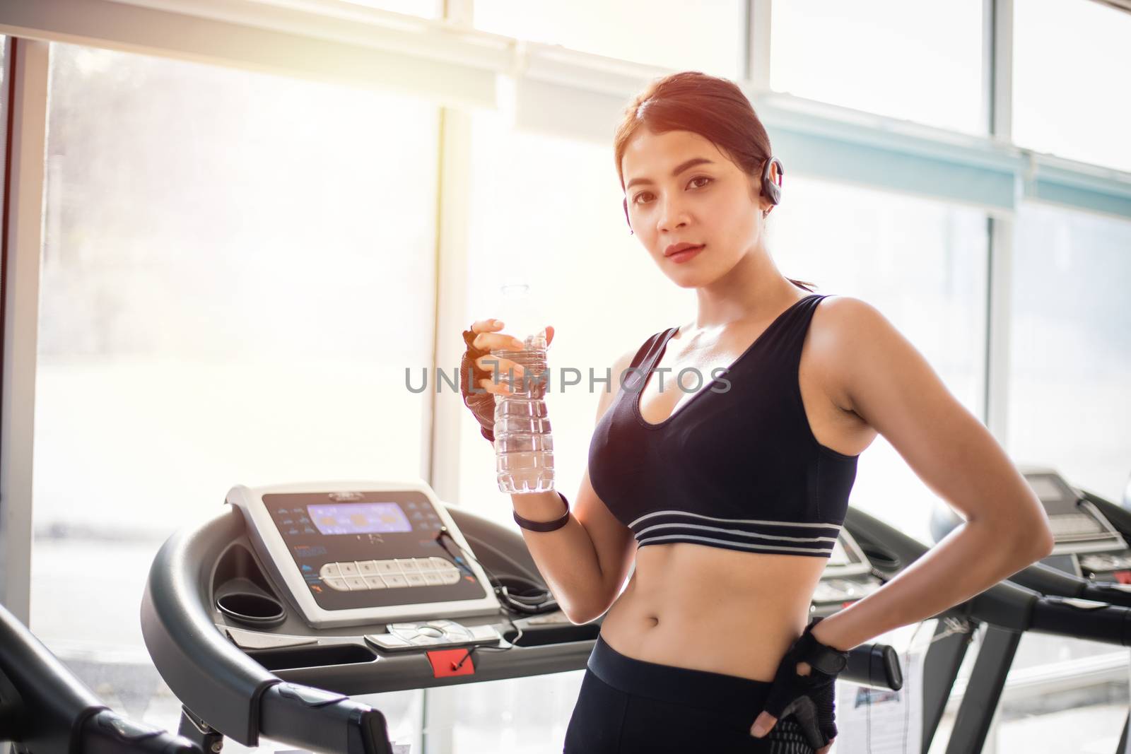 Sporty woman asia drinking water after exercises in the gym. Fitness - concept of healthy