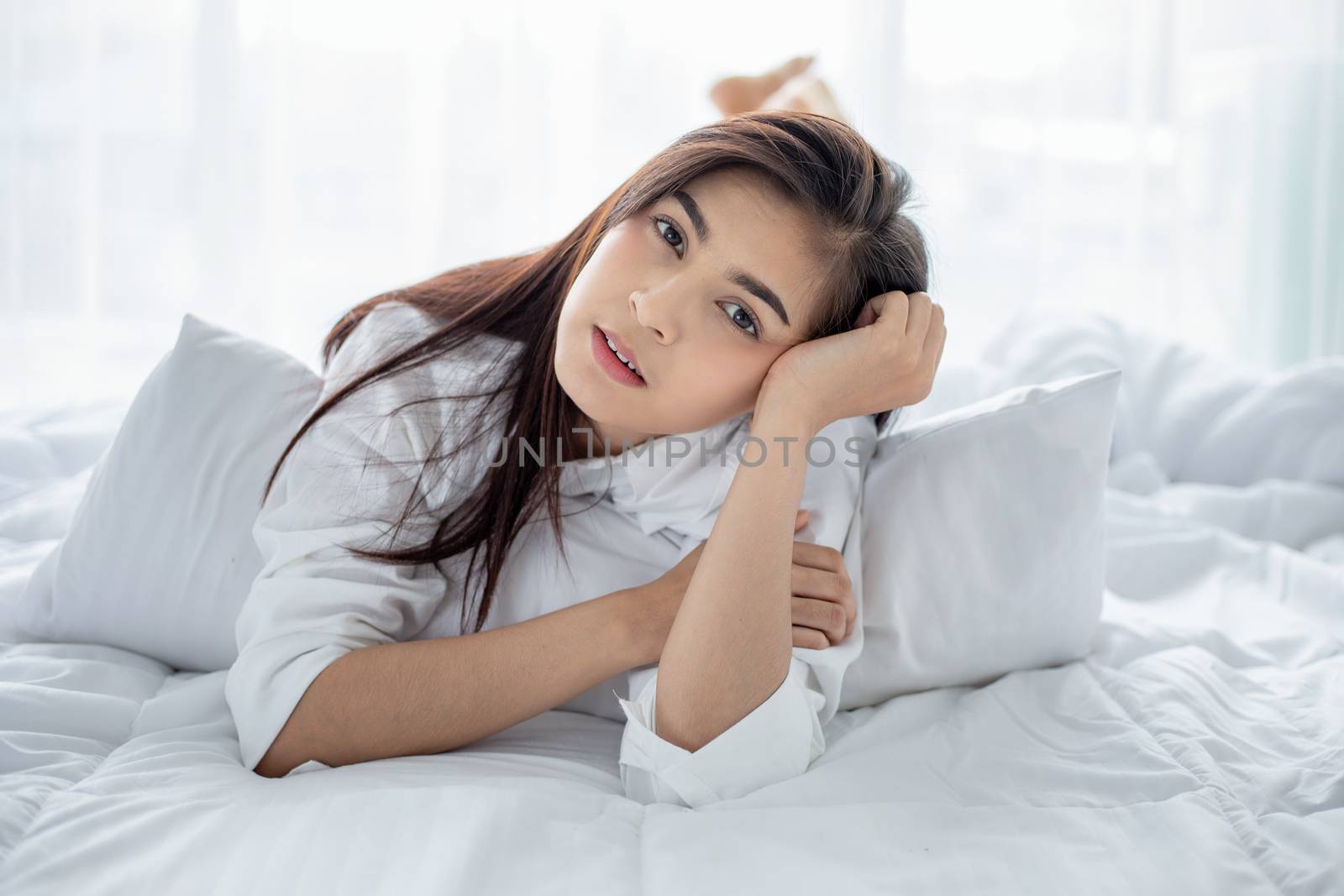 Asian woman Beautiful young smiling woman sitting and sleeping in white bed and stretching in the morning at bedroom after waking up in her bed fully rested