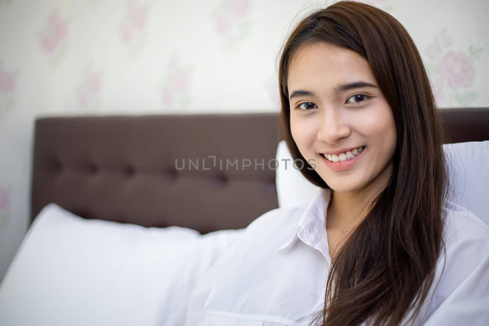 Asian women smile and are happy. After waking up on the bed