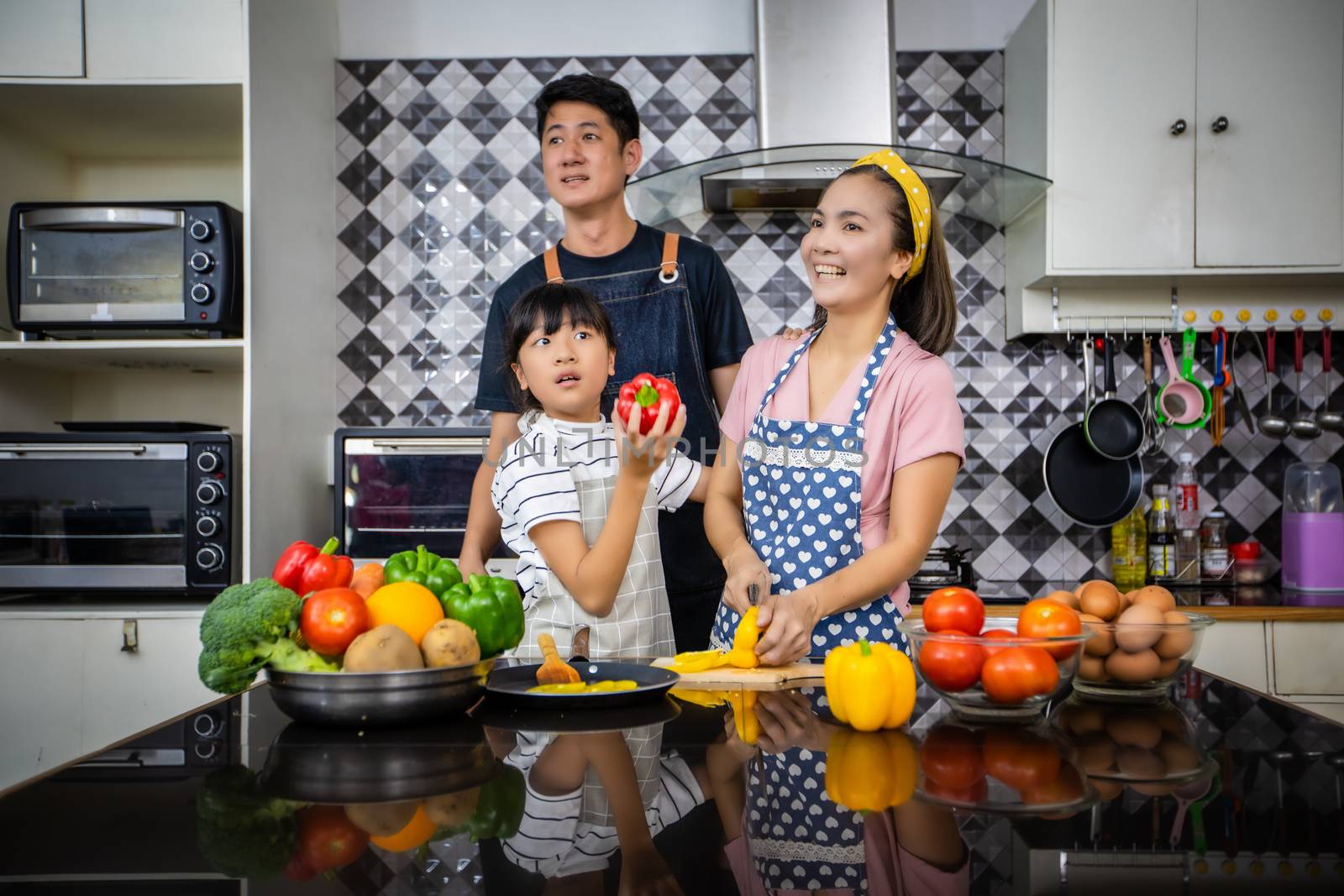 Happy Family have Dad, Mom and their little daughter Cooking Together in the Kitchen