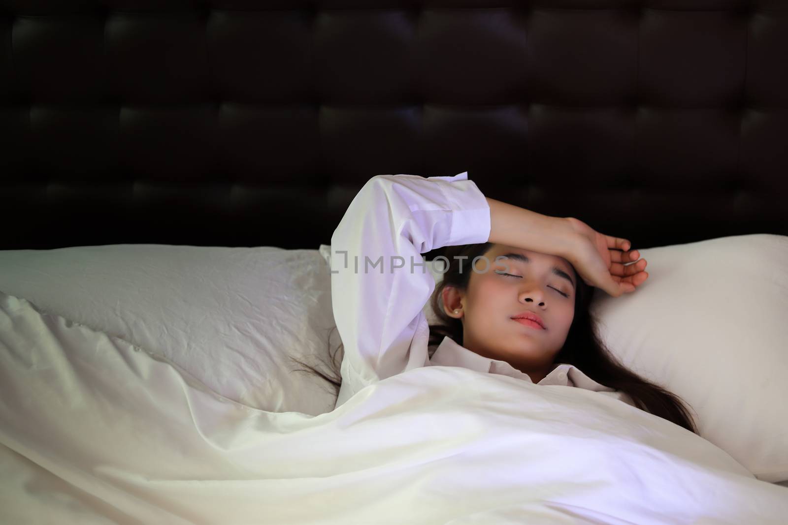 Asian woman lying down in bed on pillow put hand on face, concept of female having insomnia sleeping disorder