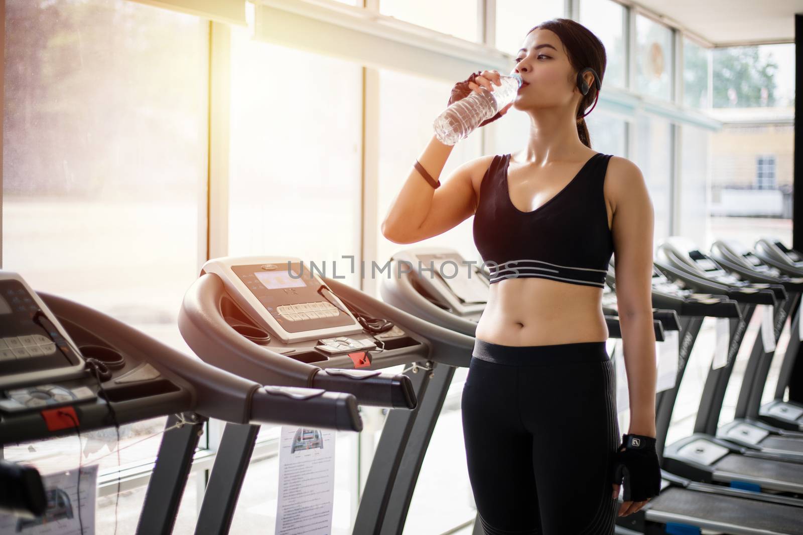Sporty woman asia drinking water after exercises in the gym. Fitness - concept of healthy