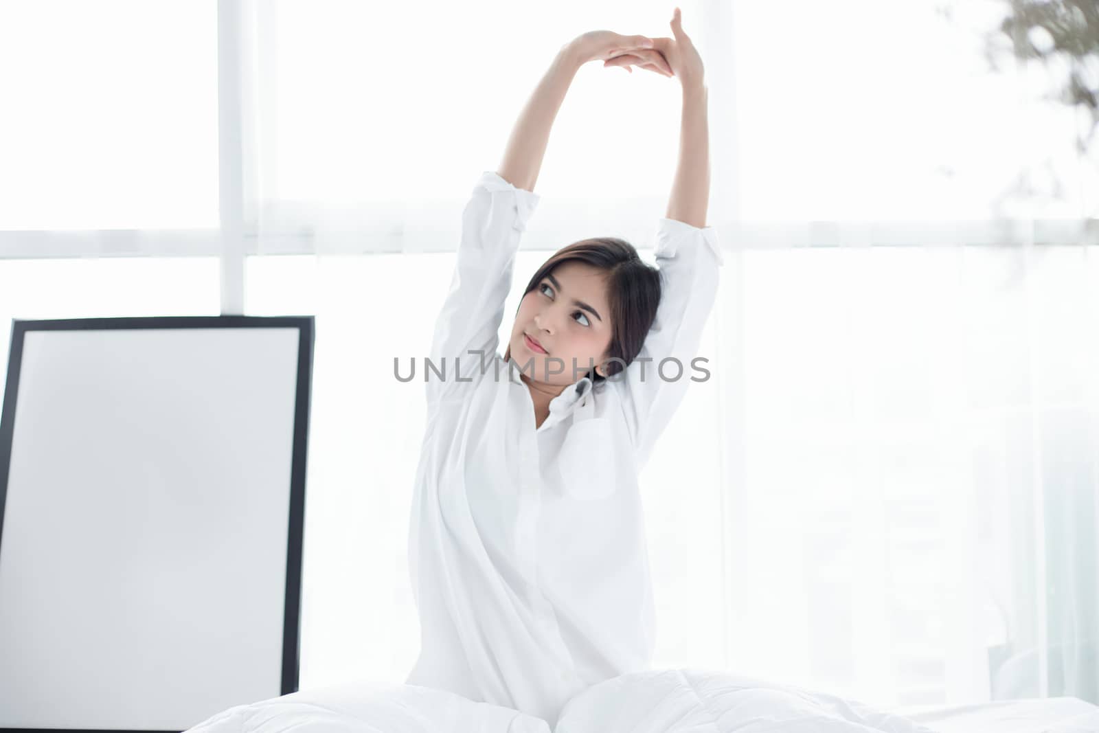 Asian woman Beautiful young smiling woman sitting and sleeping in white bed and stretching in the morning at bedroom after waking up in her bed fully rested