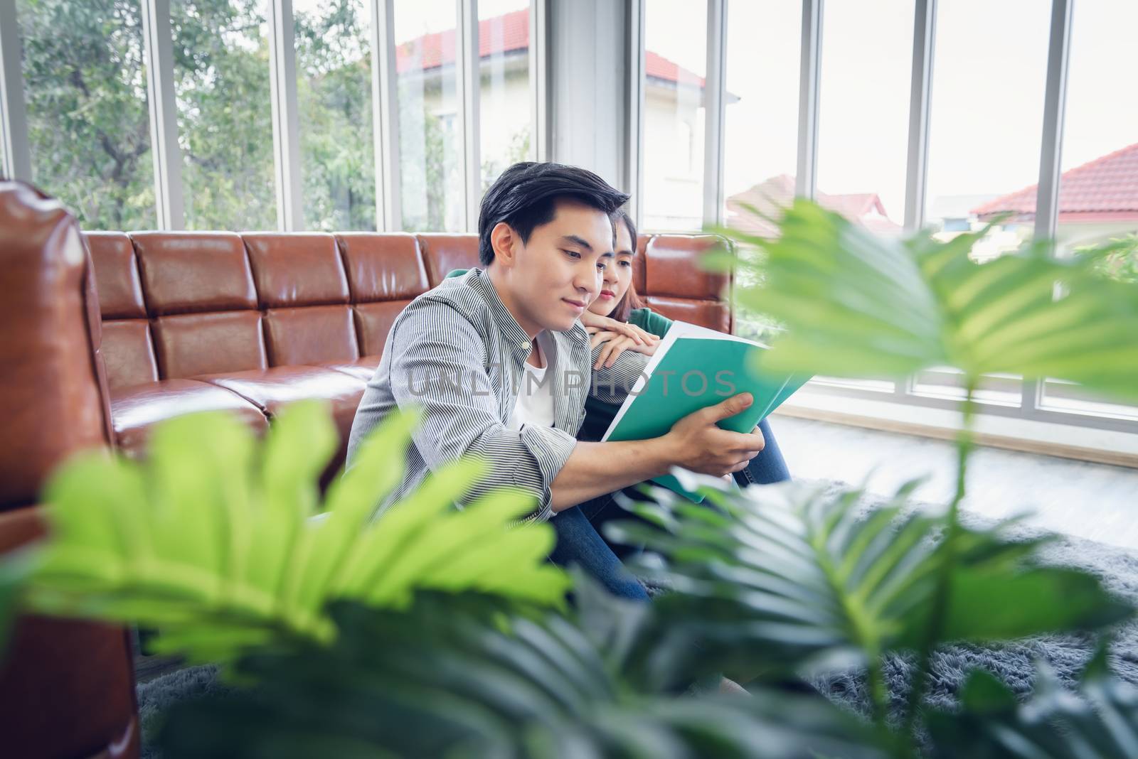 Portrait of Young Couple Love in Romantic Emotions While Reading a Book Together, Couple Young People Having Fan and Relaxing in Living Room. Happy Emotion and Relaxation Lifestyles Concept