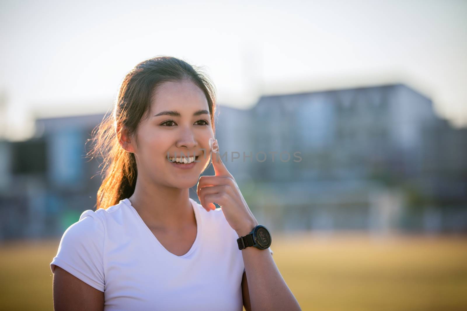 Asian Woman applying and spraying sunscreen cream on skin before run. Sports and healthy concept