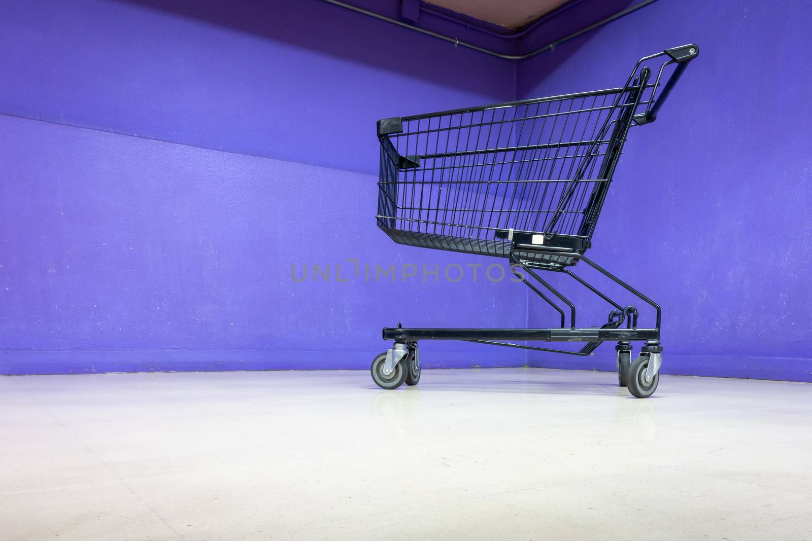 Empty Shopping Cart on Corridor Flooring in Department Store, Trolley Metal for Shopper Consumerism in Supermarket Shop. Shopping Roller Basket on The Floor Inside Customer Service Mall