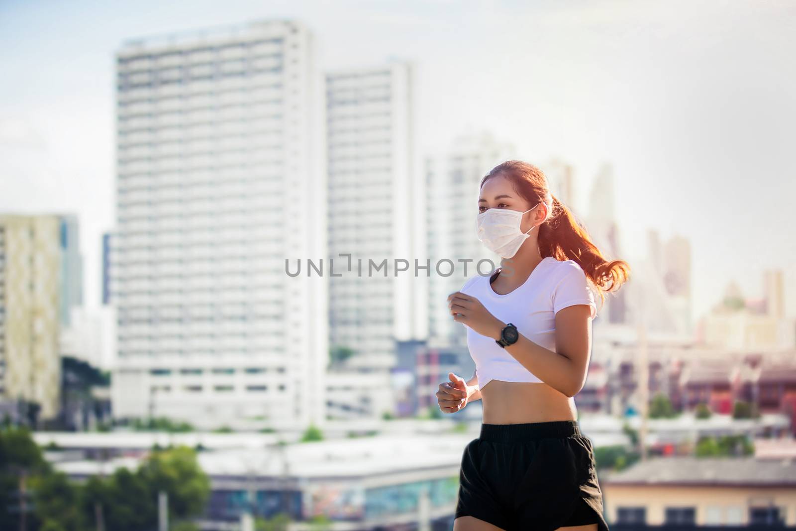 Asian Young fitness sport woman running  and she wears a  mask for protective Dust and pollution on city