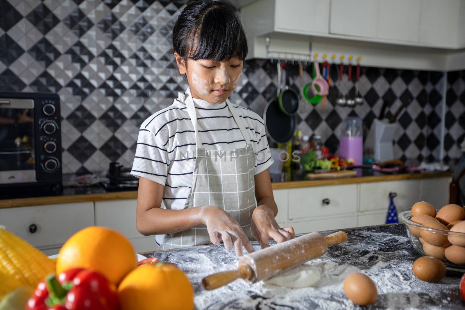 Happy Family and their little daughter preparing a pizza, knead the dough and puts ingredients on kitchen table