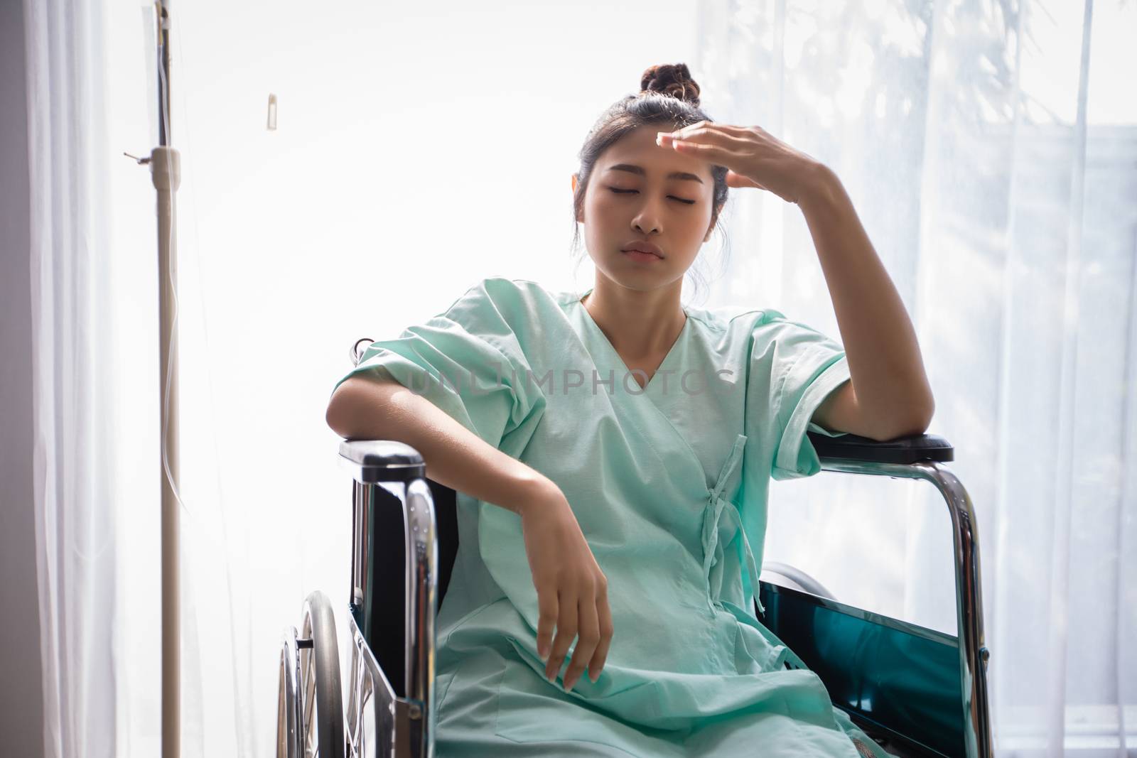 Asian Women patient on wheelchair and she is headache at a hospital