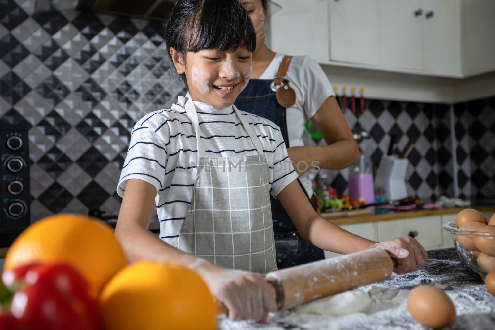 Happy Family and their little daughter preparing a pizza, knead the dough and puts ingredients on kitchen table