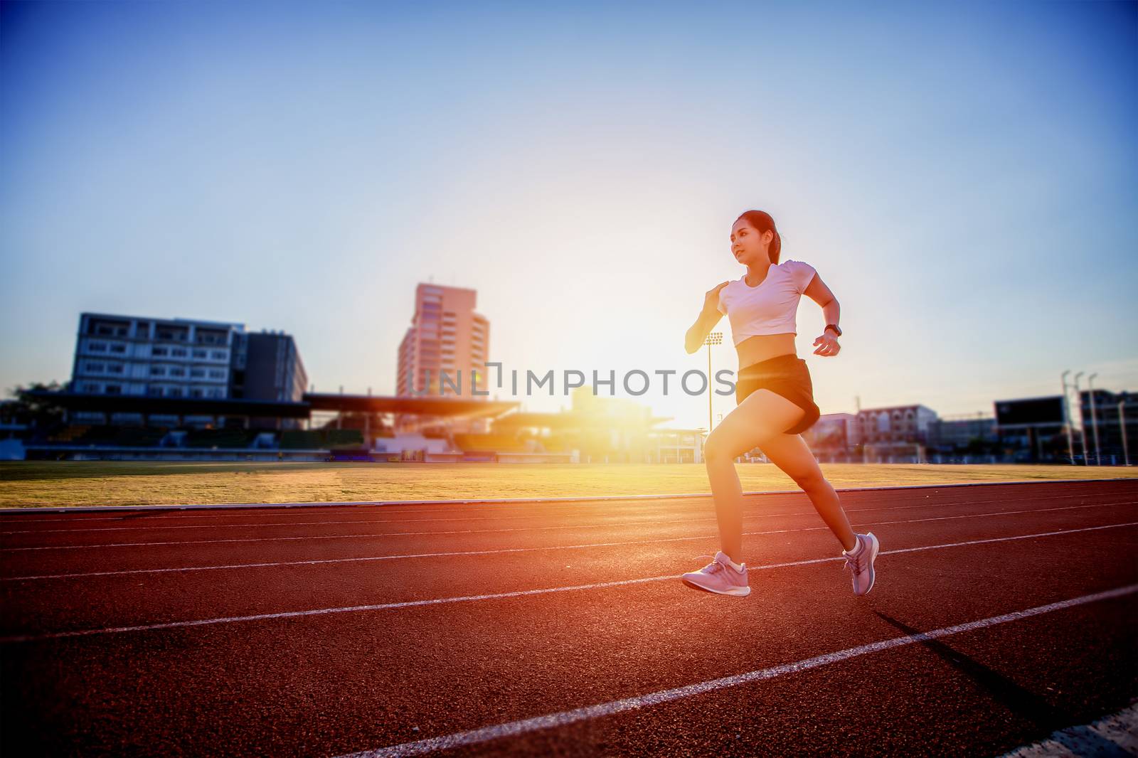 Asian Young fitness woman runner running on stadium track 