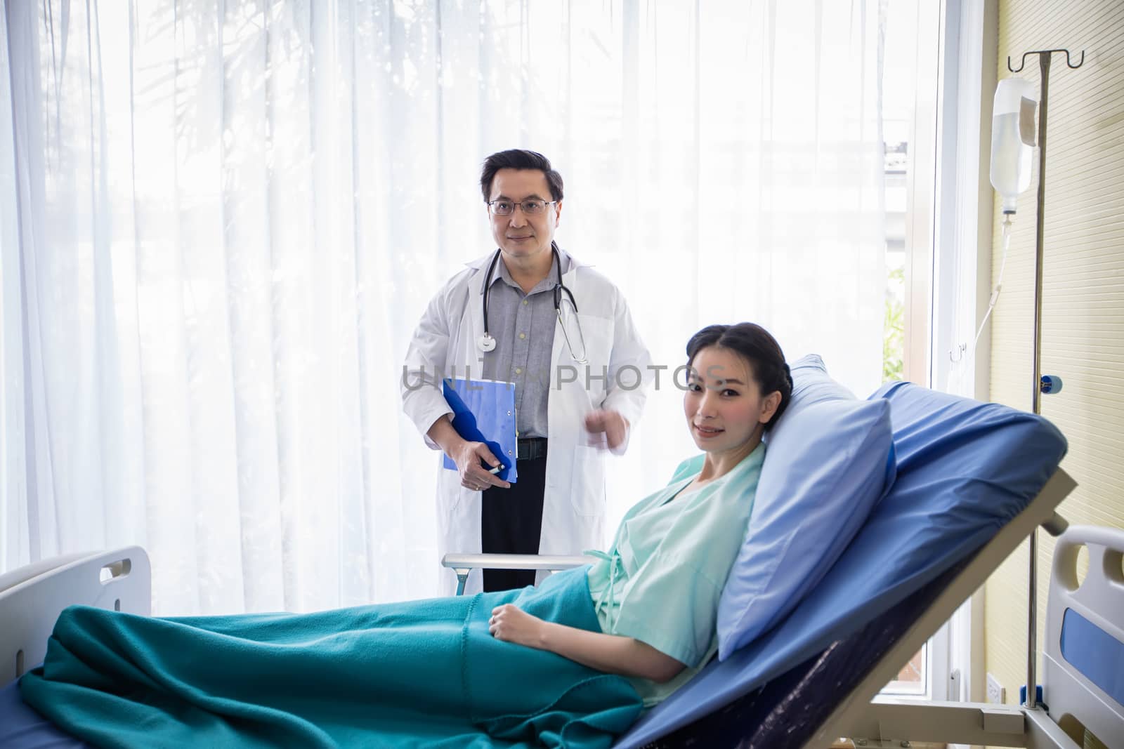 The doctors are asking and explaining about the illness to a female patient lying in bed at a hospital.