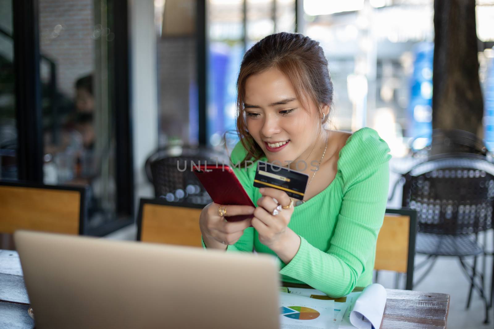 Asian women drinking coffee in a cafe and shopping online and paying with credit card on smart phones