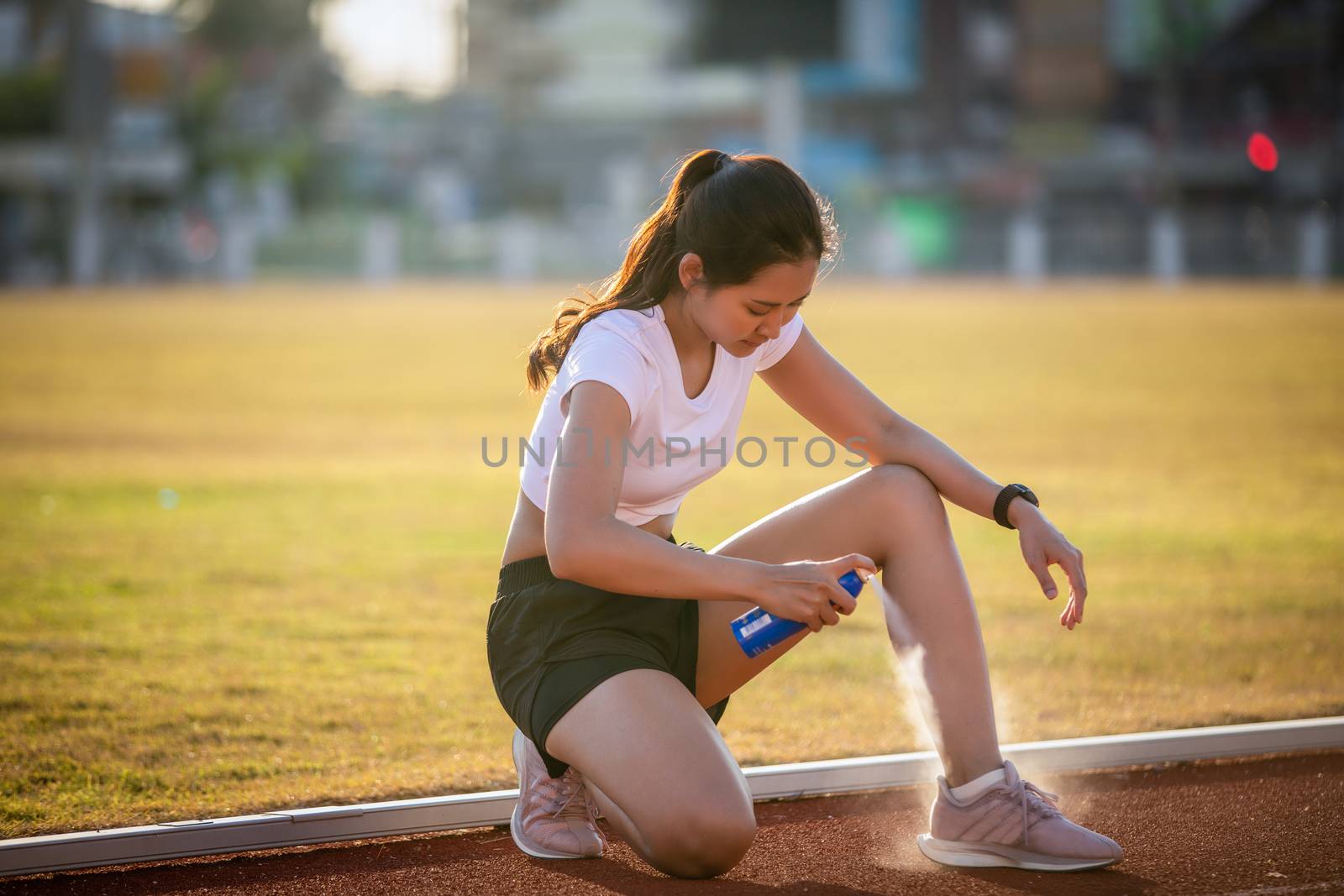 Asian Sports women using freezing spray for treating injured sportwomen's knee and leg  after run