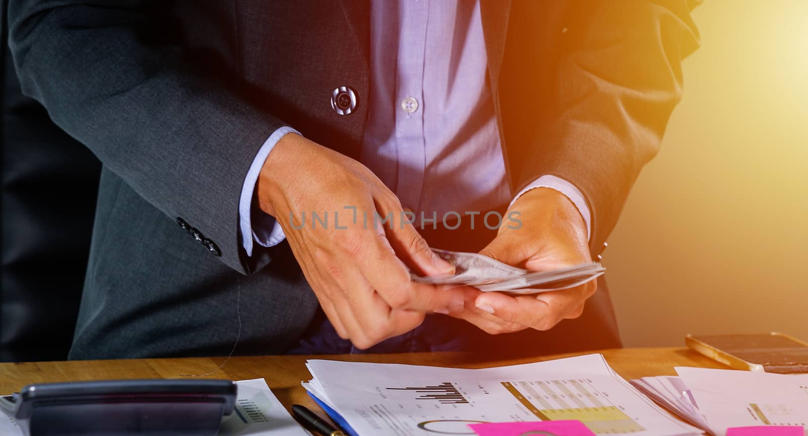 Businessmen count money and plan finances for projects and use calculators for analysis project documents and graph financial diagram working in the background on office table