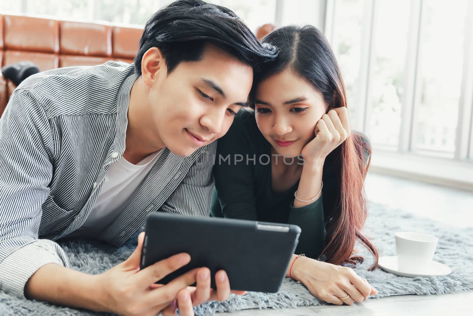 Young Couple Love Relax Enjoyment While Online Shopping on Electronic Tablet in Living Room, Portrait of Asian Couple Relaxing on a Couch During Shopping Online Togetherness. Relaxation/ Lifestyle