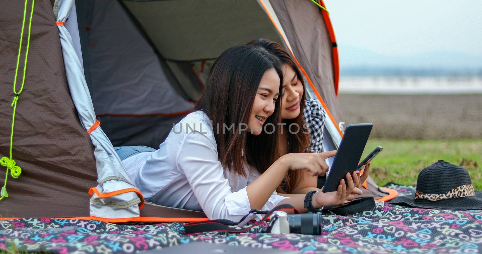 A group of Asian friends playing Ukelele and spending time making a picnic in the summer holidays.They are happy and have fun on holidays. They using notebook for working