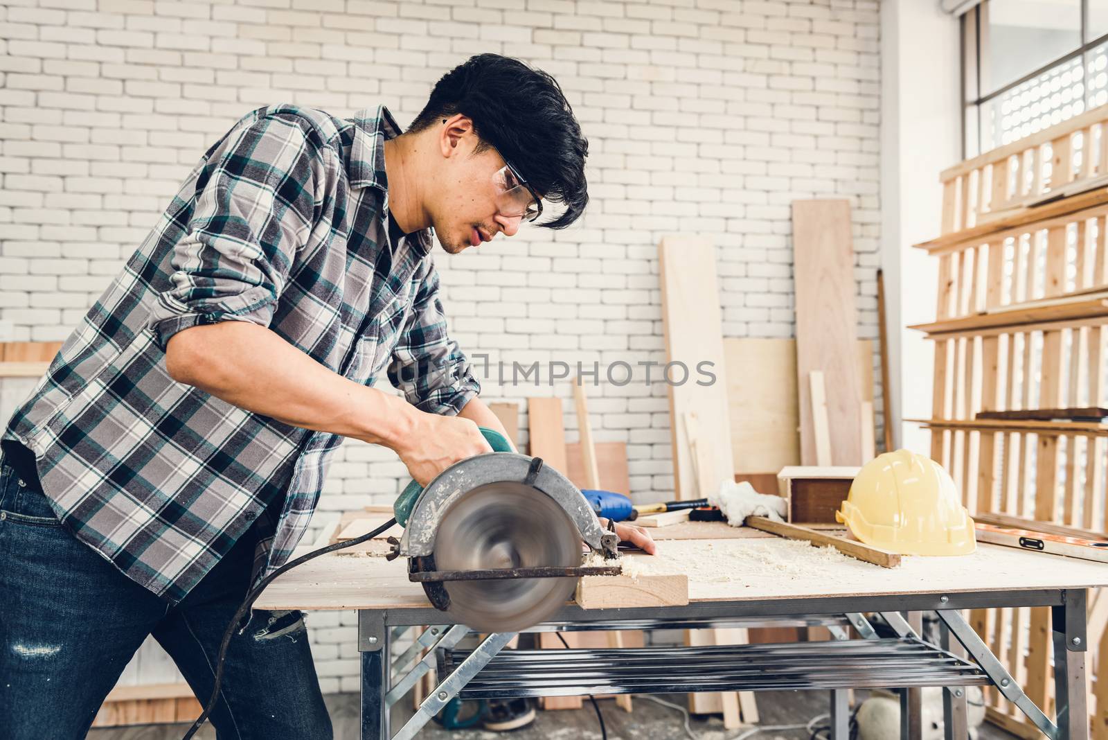 Carpenter Man is Working Timber Woodworking in Carpentry Workshops, Craftsman is Using Sawing Machine Cutting Timber Frame for Wooden Furniture in Workshop. Workmanship and Job Occupation Concept by MahaHeang245789
