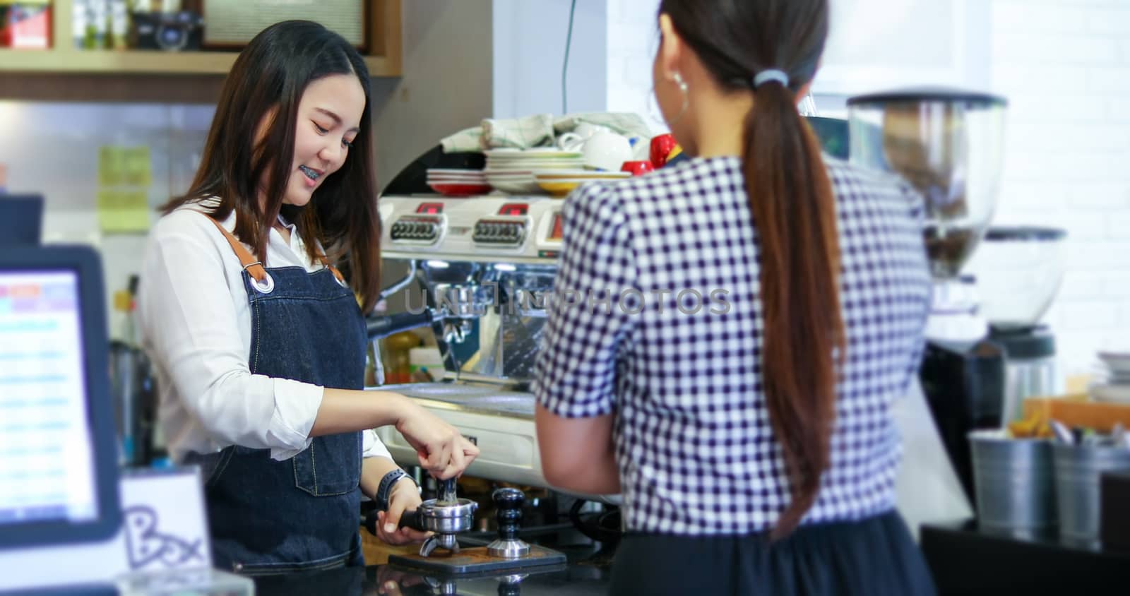 Barista serving customer and Woman is paying for coffee by credit card in coffee shop