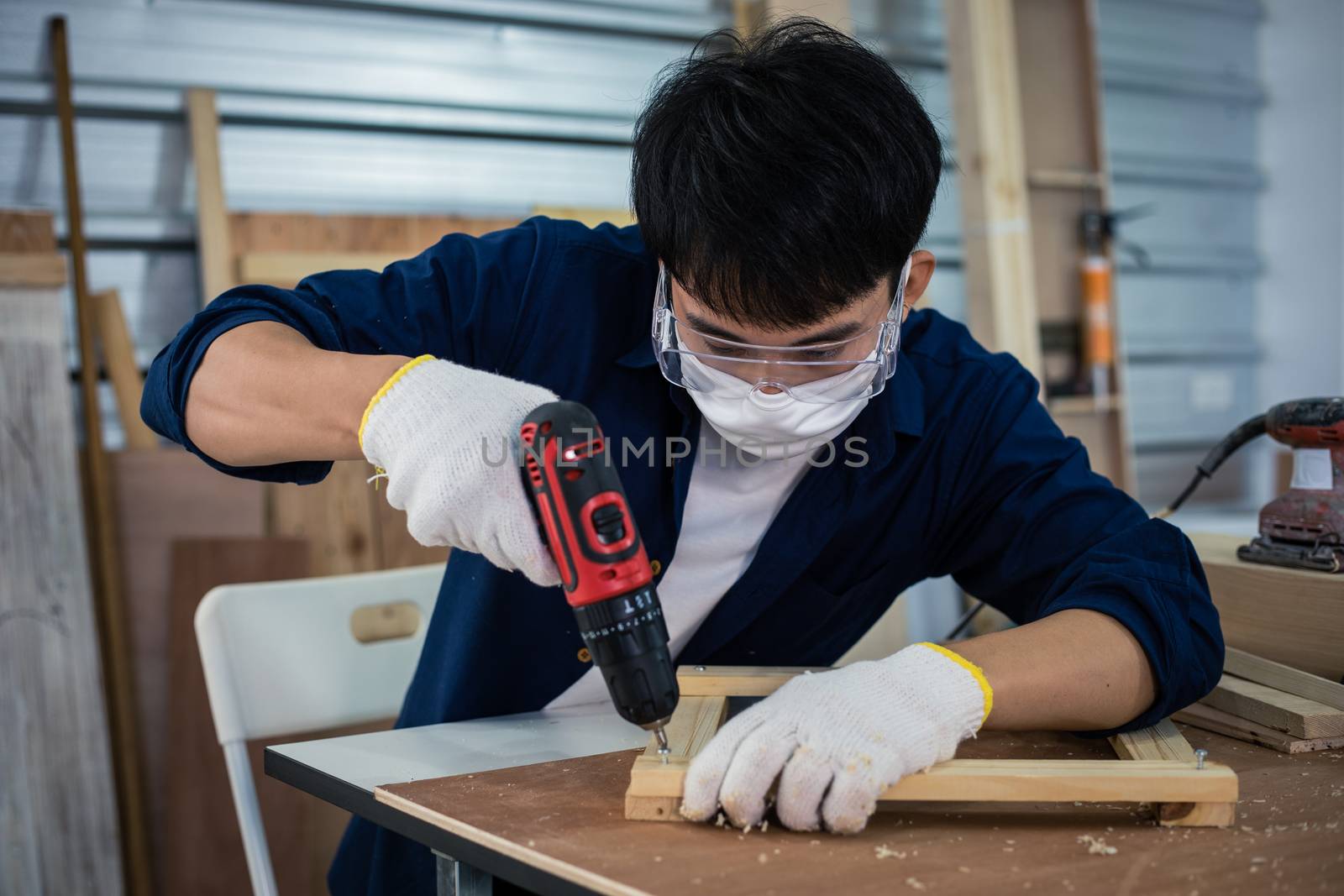 Asian man Carpenter working with technical drawing or blueprint construction paper lying on a workshop with carpentry tools and wood at home