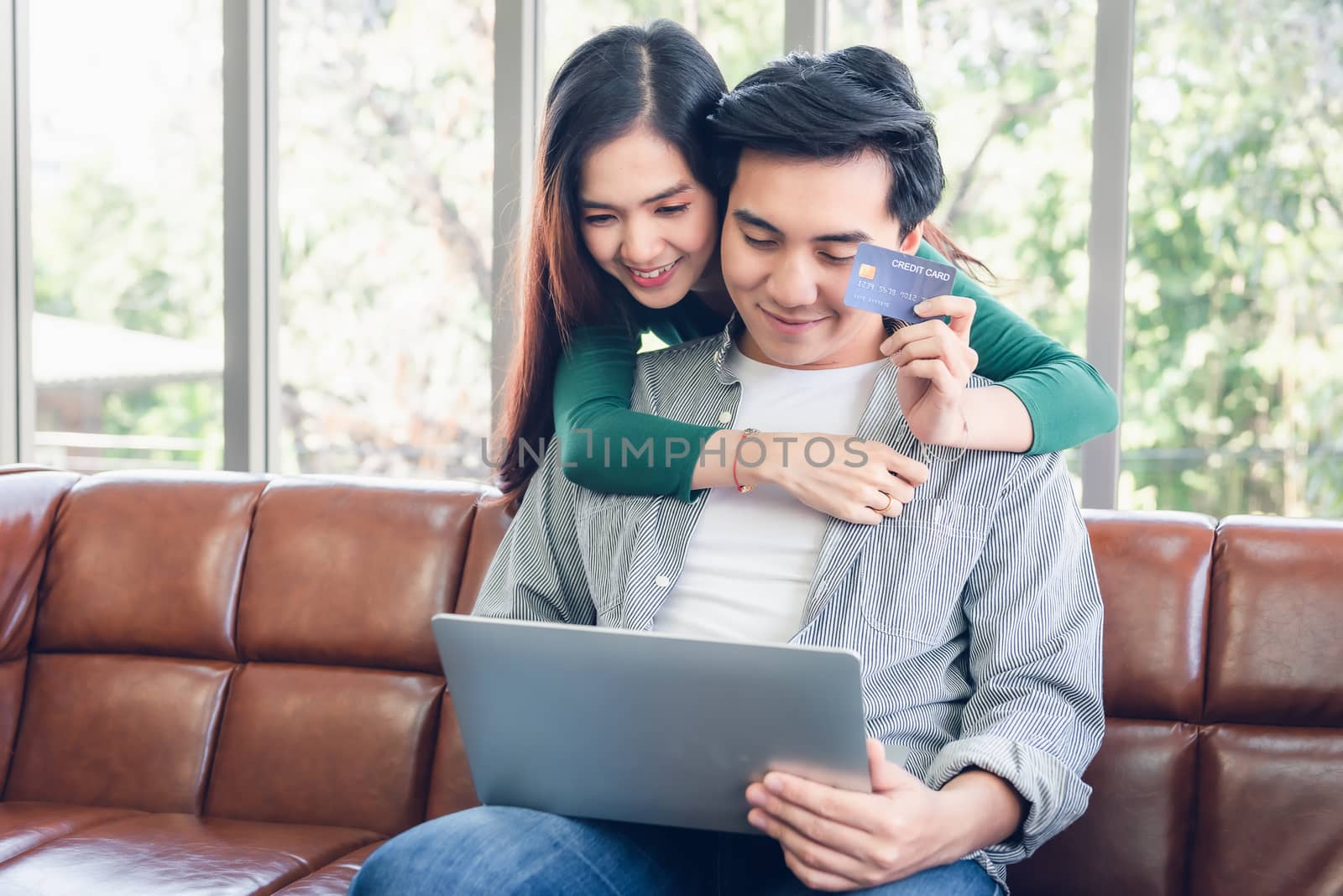 Couple Love Having Enjoy Relaxation on Sofa at Their Home, Attractive Asian Couple Happiness in Romantic Moments at Living Room While Online Shopping and Work at Home. Relaxing and Lifestyles Concept
