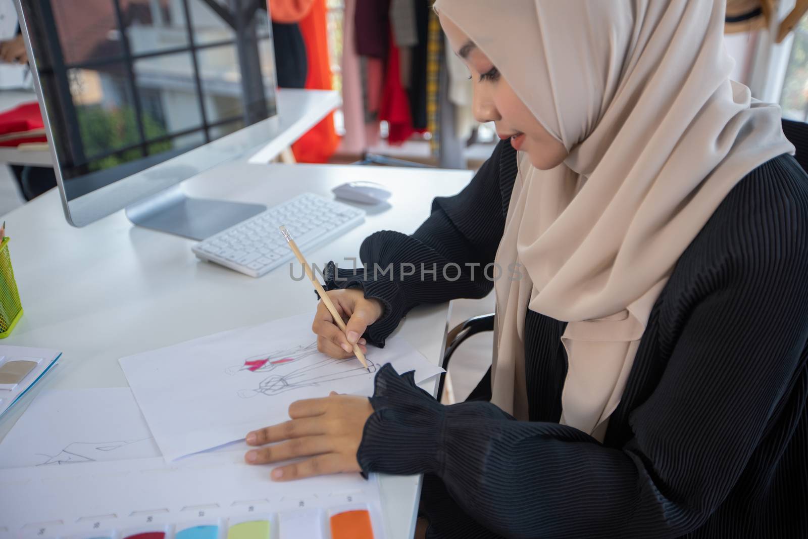 Small business of Muslim woman fashion designer Working and  using smart phone and tablet With Dresses at clothing store