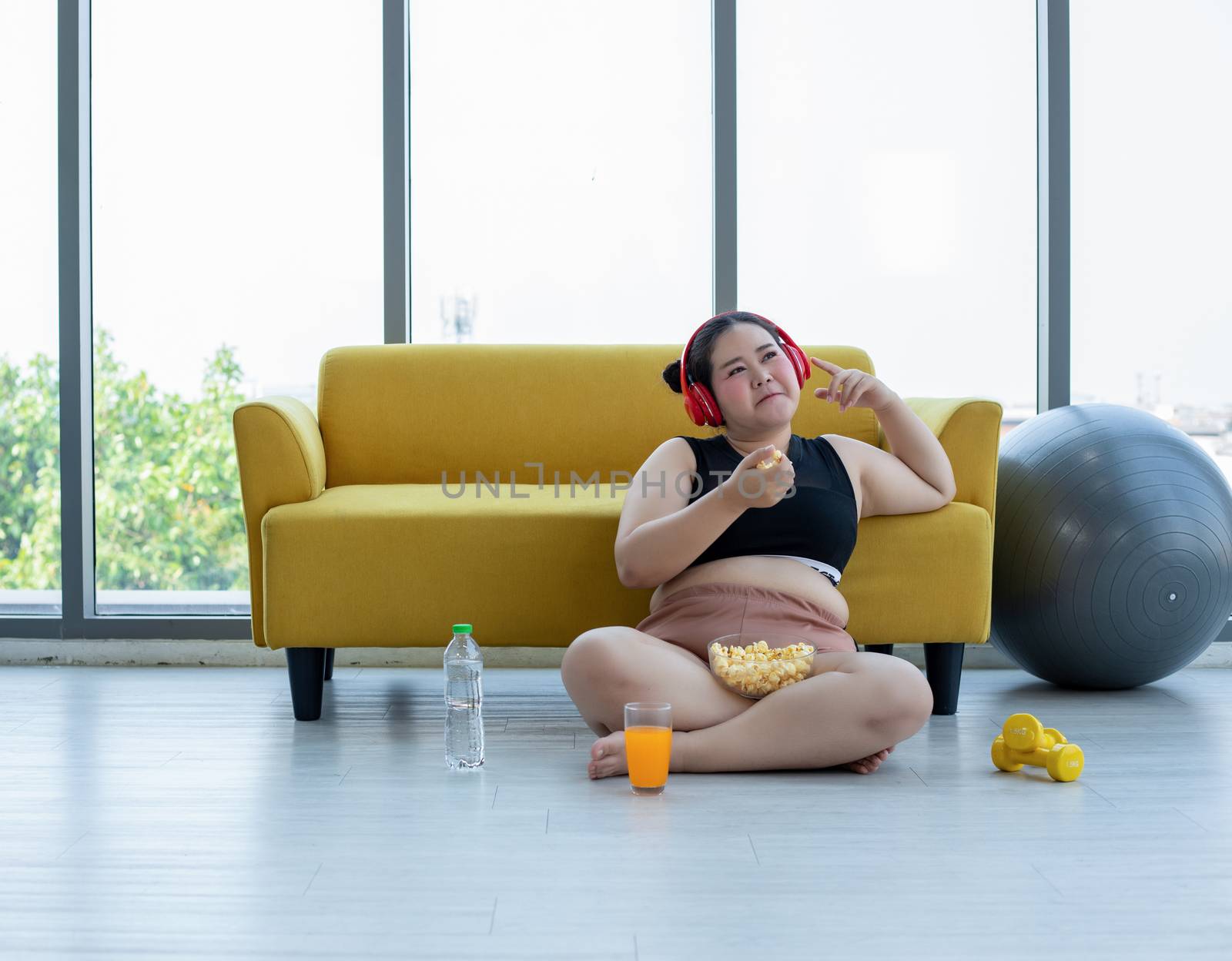 Overweight woman and asian girl enjoy eating food on sofa at home