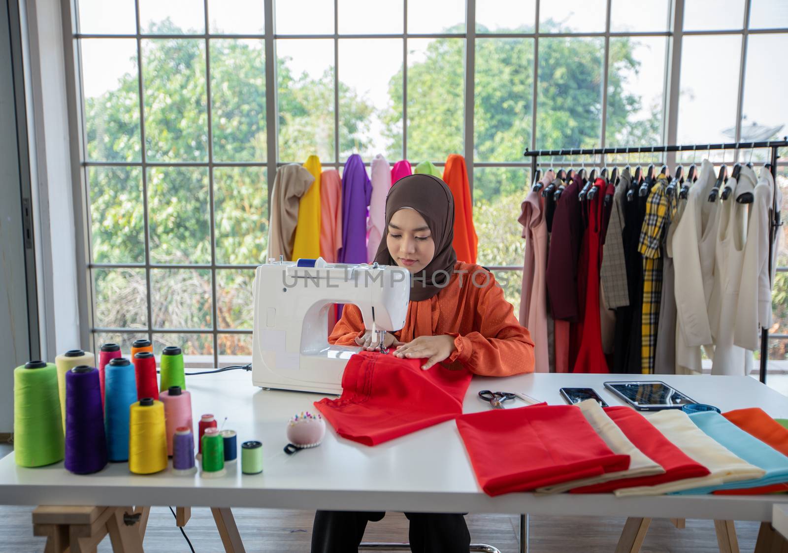 Small business of Muslim woman fashion designer Working and  using smart phone and tablet With Dresses at clothing store