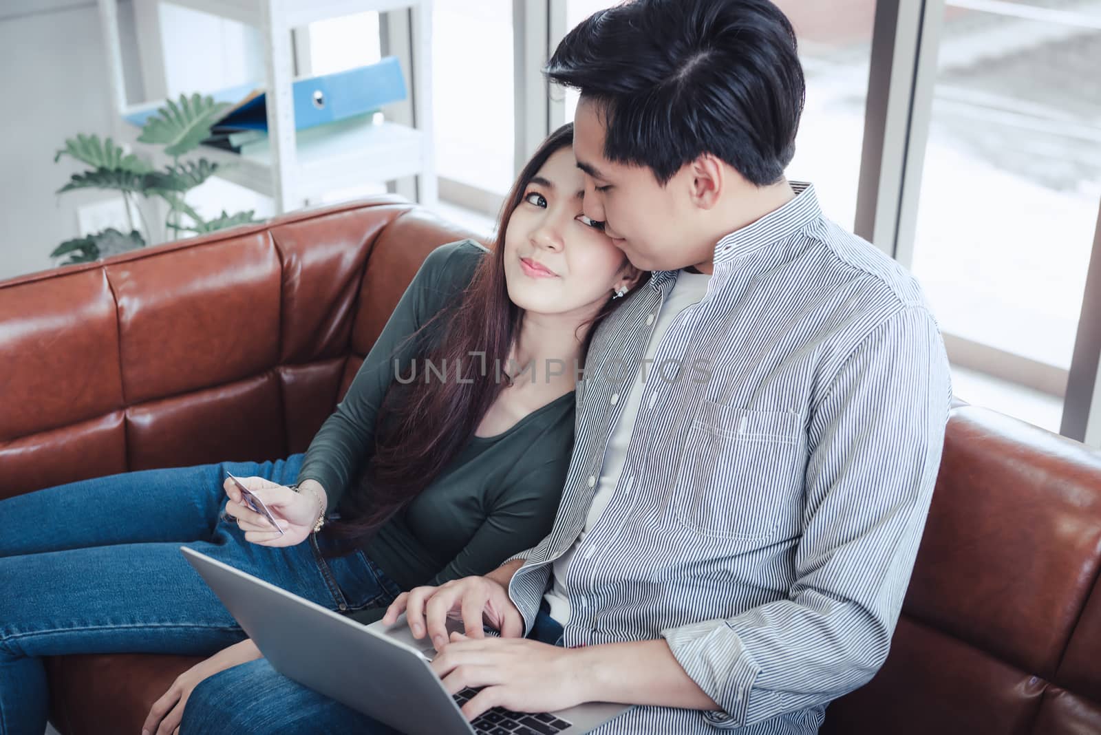 Couple Love Having Enjoy Relaxation on Sofa at Their Home, Attractive Asian Couple Happiness in Romantic Moments at Living Room While Online Shopping and Work at Home. Relaxing and Lifestyles Concept by MahaHeang245789