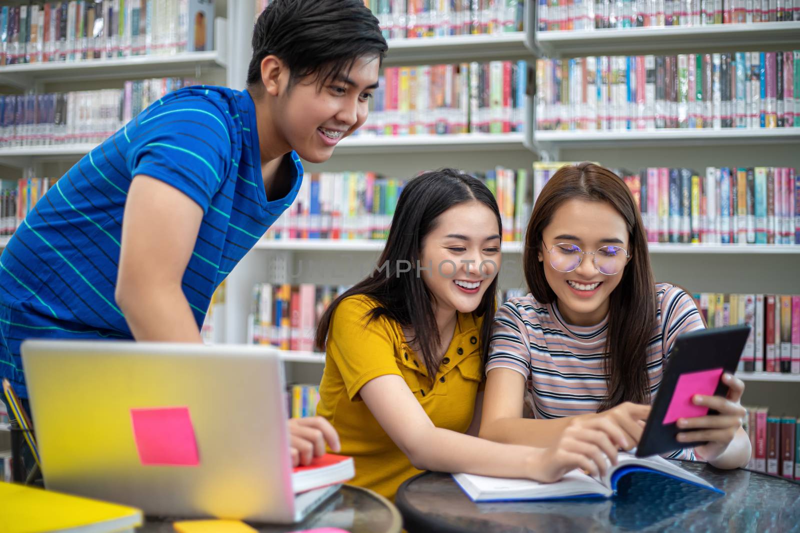 Group Asian  Students Smile and reading book and using notebook for helps to share ideas in the work and project. And also review the book before the exam