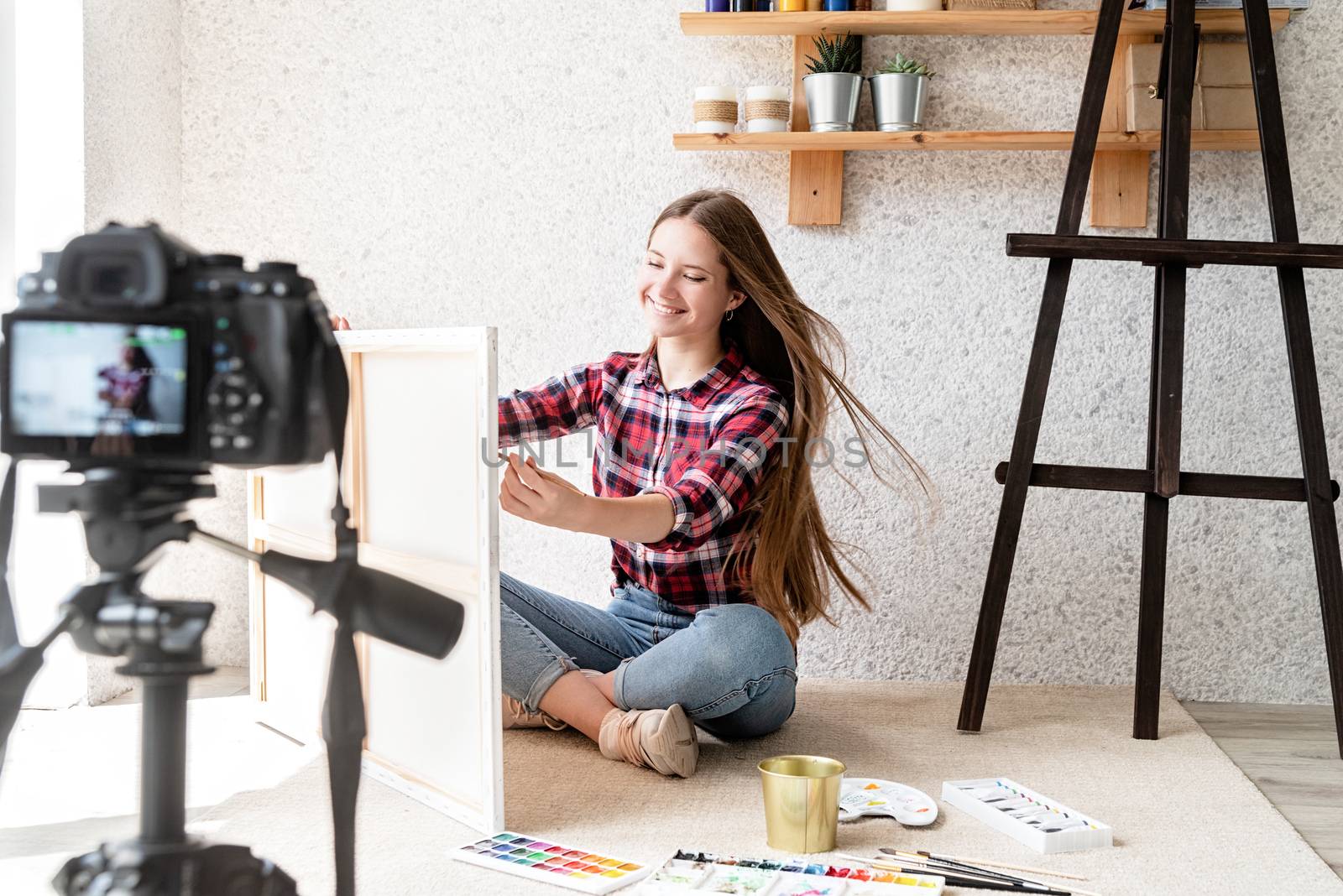 Woman making a video for her blog on art using a tripod mounted digital camera by Desperada