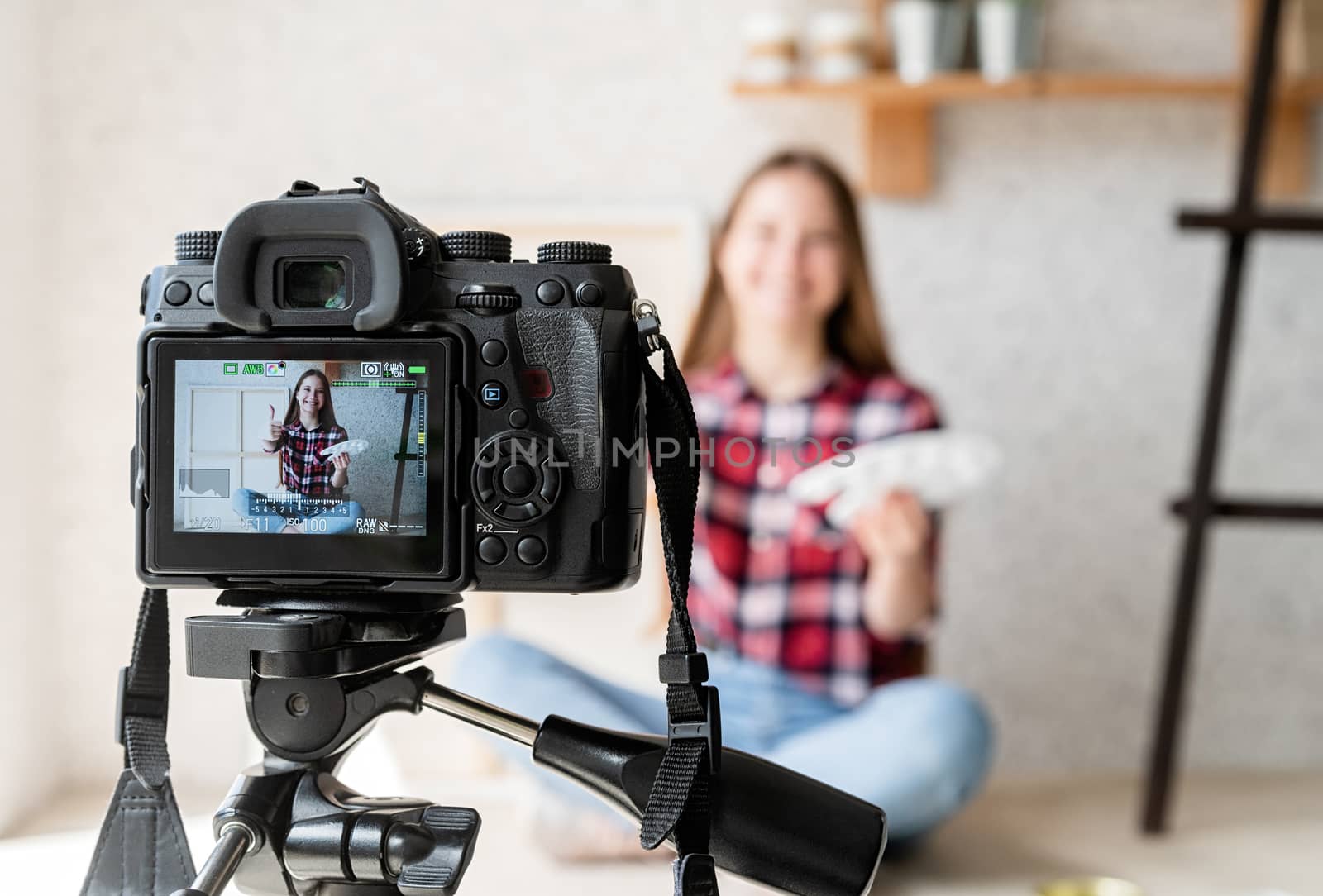 Woman making a video for her blog on art using a tripod mounted digital camera by Desperada