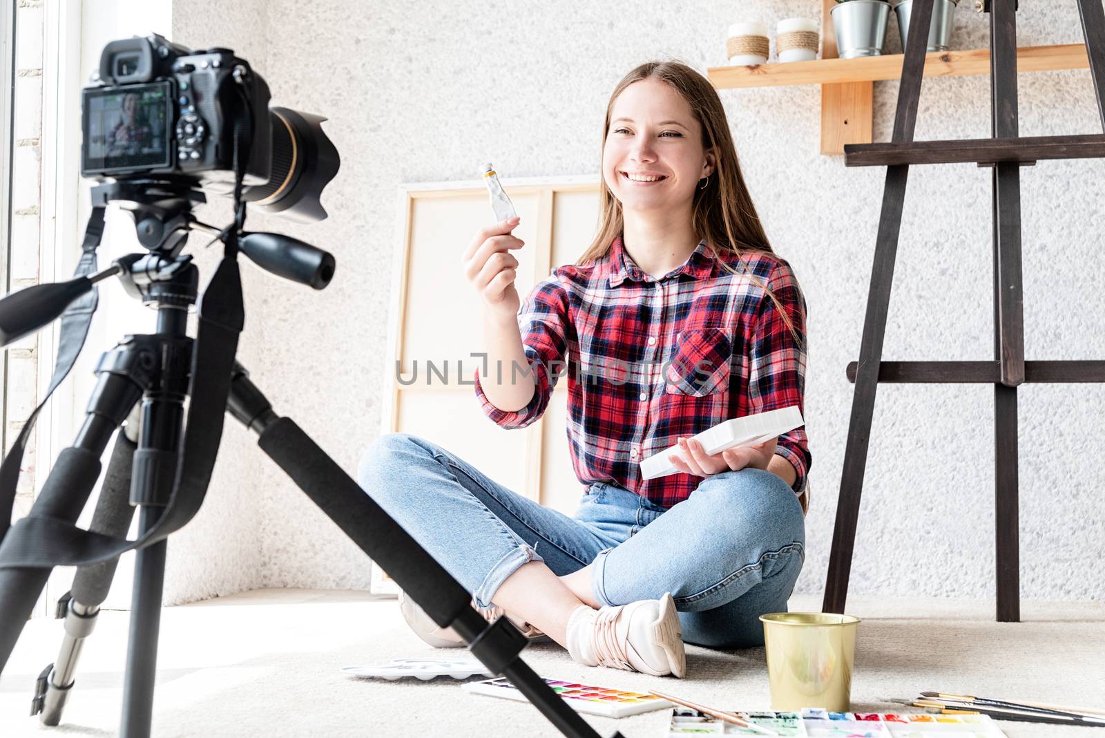 Woman making a video for her blog on art using a tripod mounted digital camera by Desperada