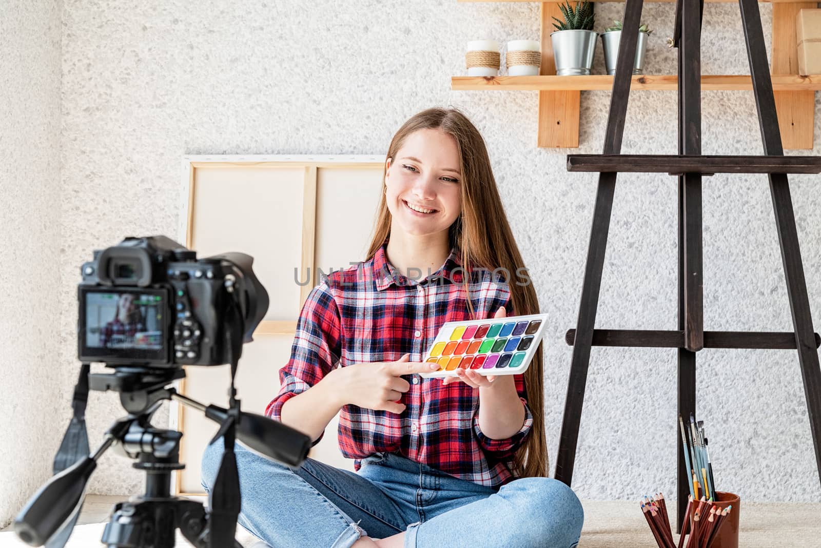 Young artist woman blogger making a video for her blog on art showing watercolor paints
