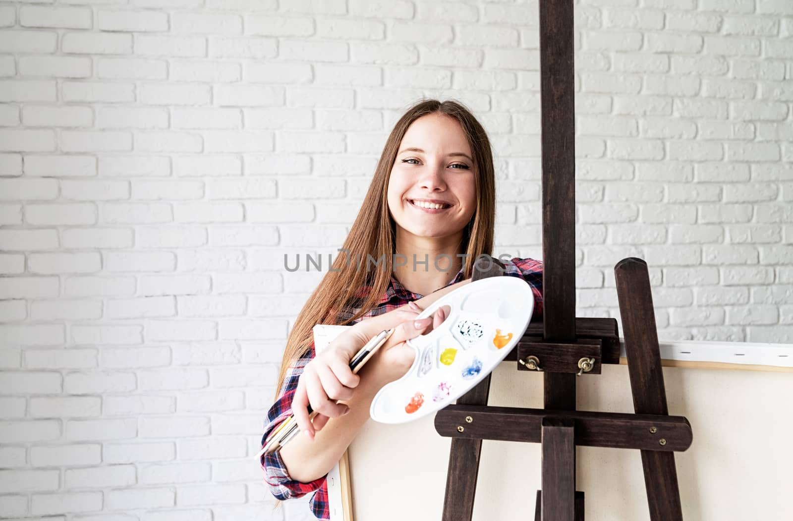 Beautiful smiling woman artist with color palette and paintbrushes by Desperada