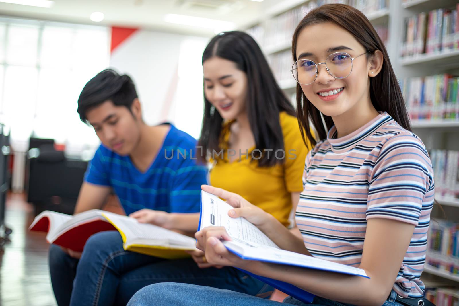 Group Asian  Students Smile and reading book and using notebook for helps to share ideas in the work and project. And also review the book before the exam