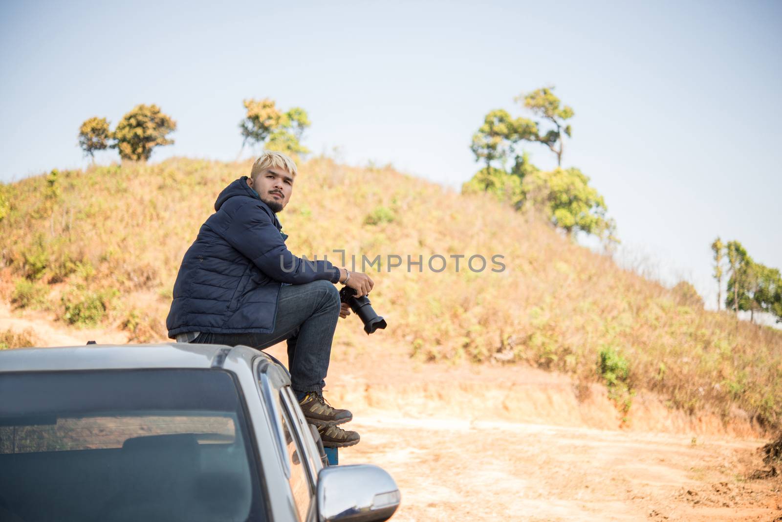 Young photographer sitting on his pickup truck photographing in mountain.