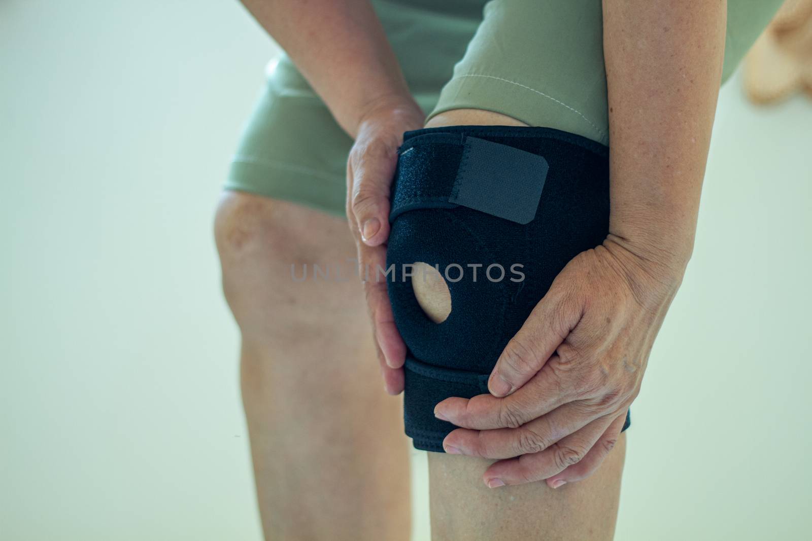 old Asian women to knee injury and use knee support brace on leg 