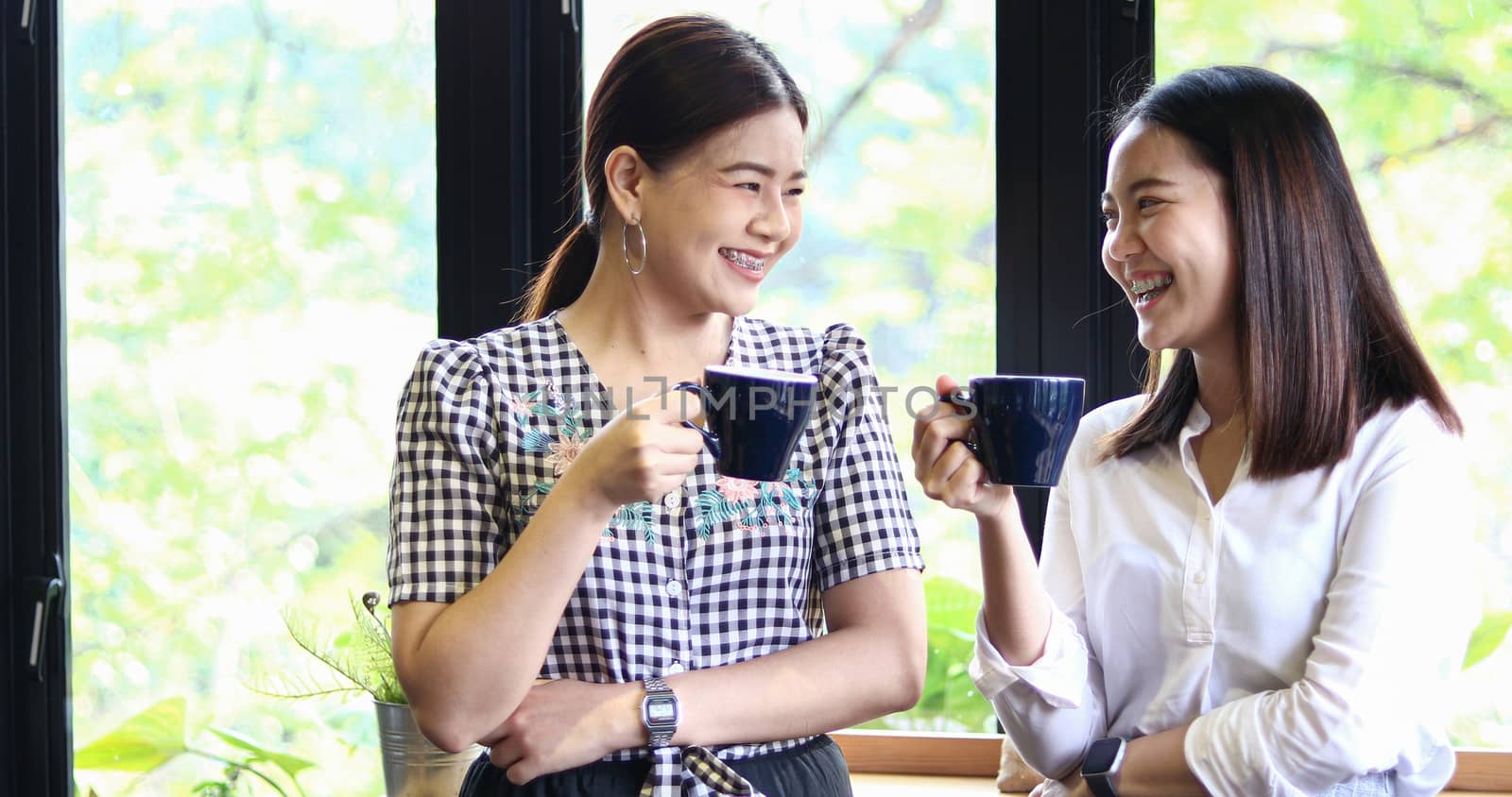 Two asian women drinking coffee and Cheerful women gossiping in a cafe