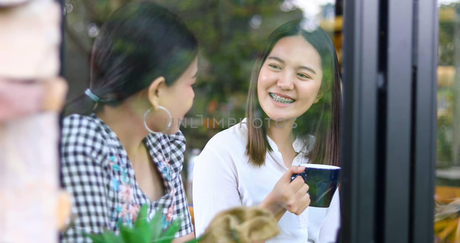 Two asian women drinking coffee and Cheerful women gossiping in a cafe