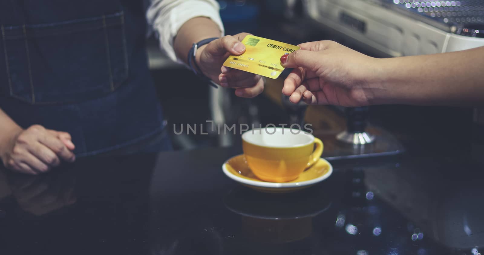 Barista serving customer and Woman is paying for coffee by credit card in coffee shop