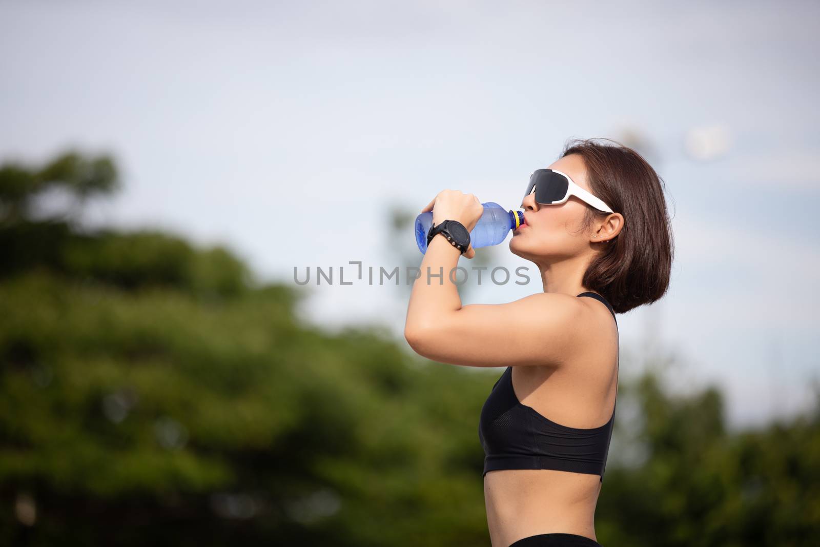 Sporty woman asian drinking water outdoor  after running on sunny day