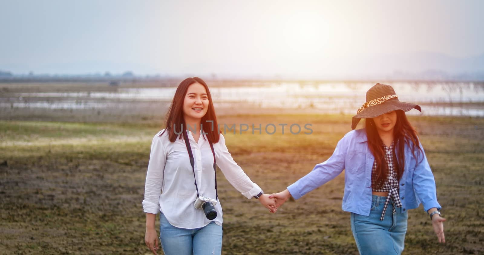Asian Young women are having fun and laughing and hugging on the green field in the evening. by Tuiphotoengineer