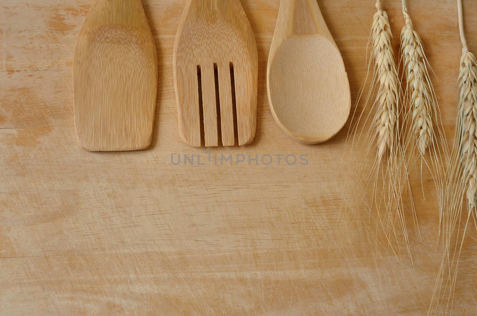 Wooden kitchen utensils and wheat on wooden background by Kheat