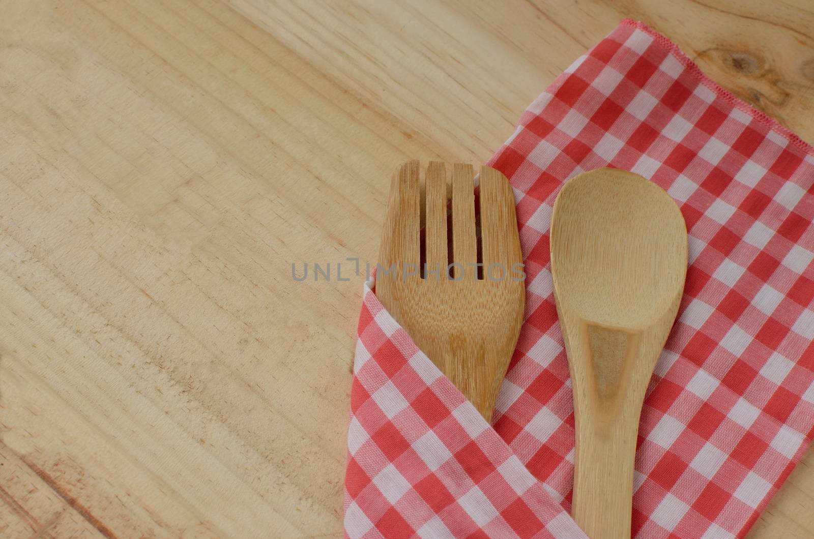 Wooden kitchen utensils and fabric on wooden background