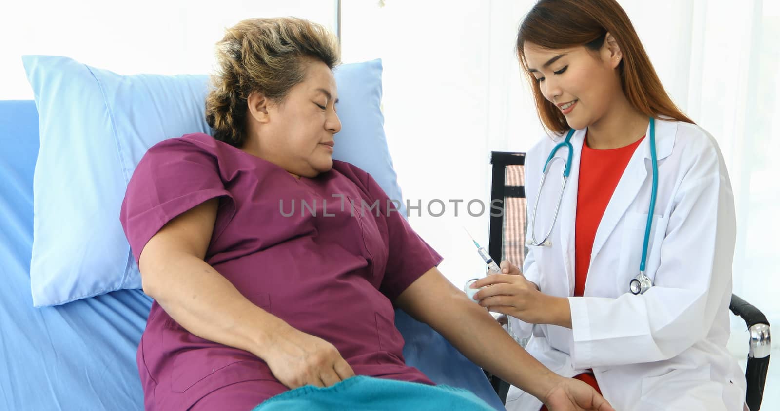 The doctor is using the syringe for the old woman lying in bed