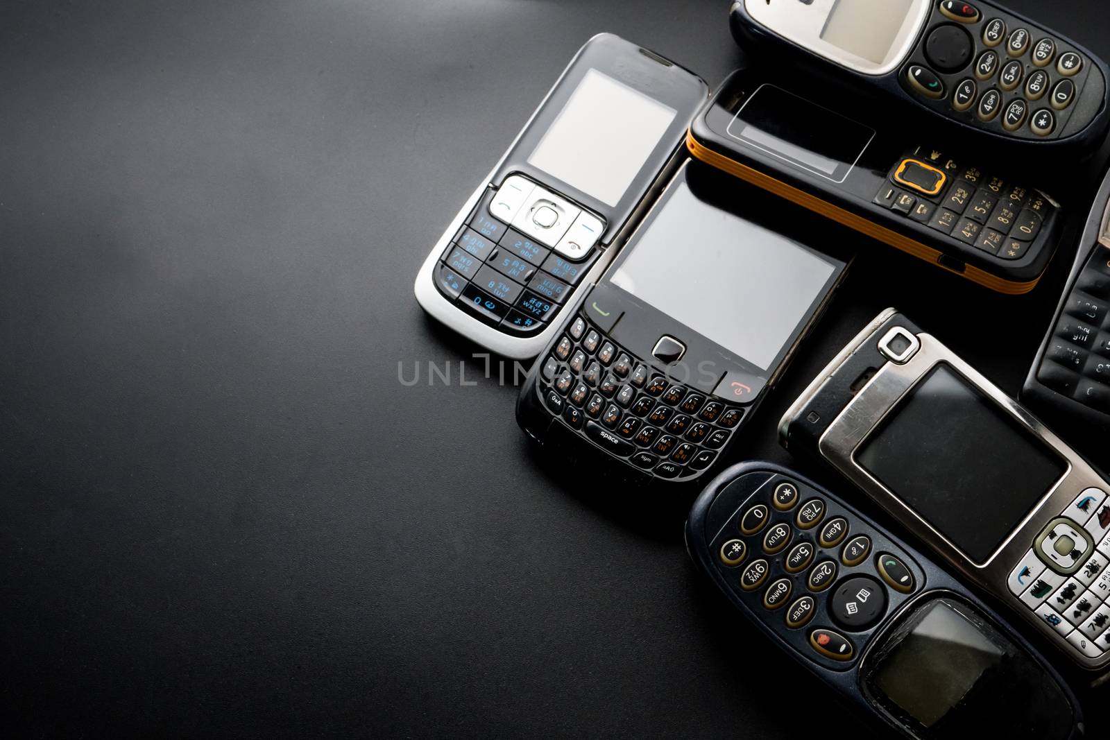 Old and obsoleted cellphones on a black background. by ronnarong