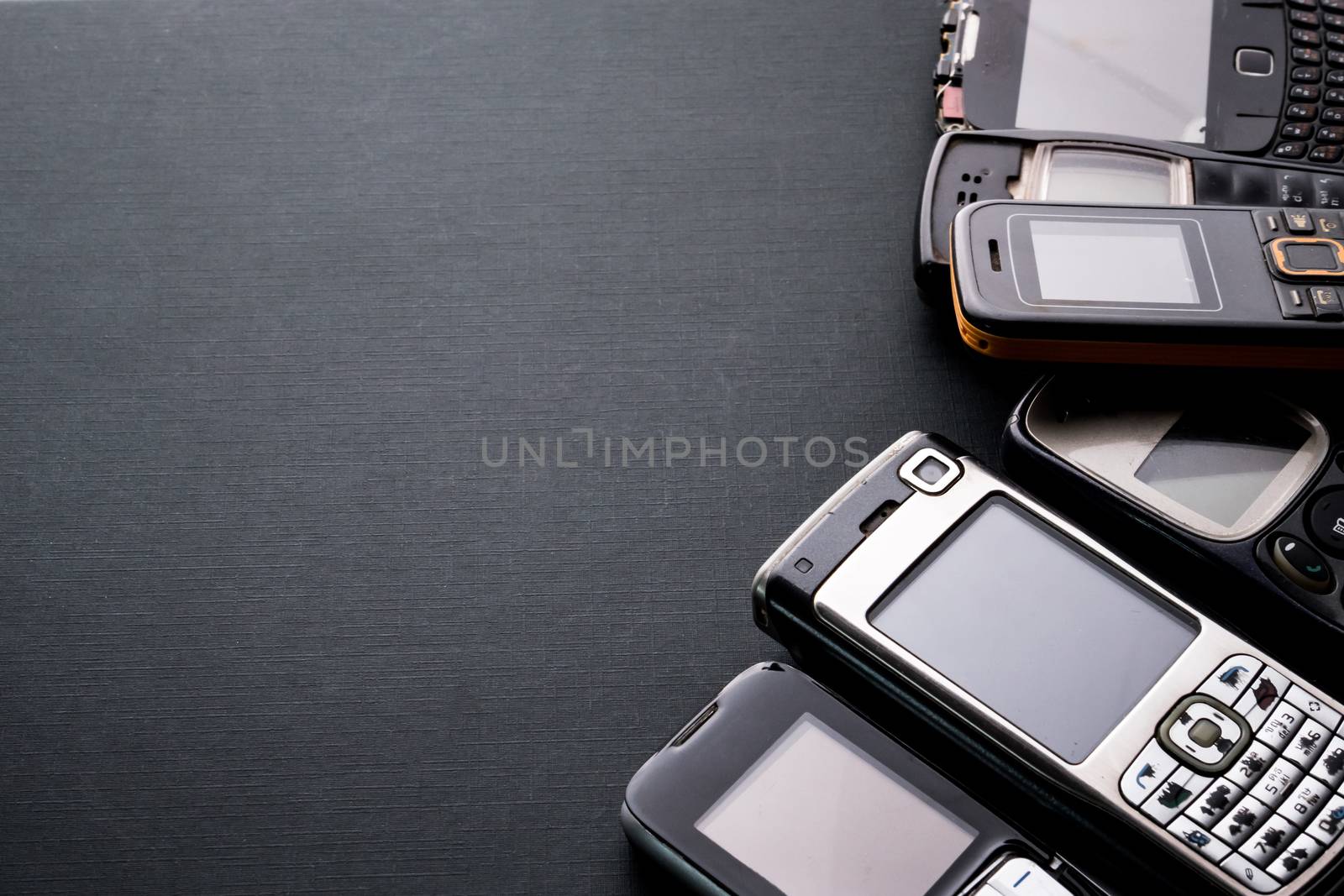 Old and obsoleted cellphones on a black background.