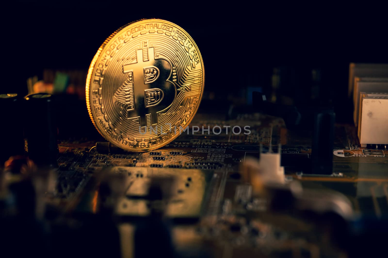 A golden coin with bitcoin symbol on a mainboard. by ronnarong
