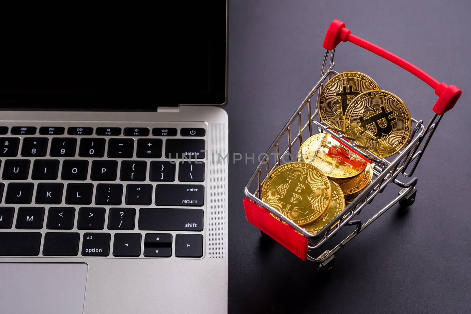 Golden coins with bitcoin symbol in a little shopping cart and a computer.